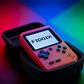 Red Fidgix Nano Plus™ with 'FIDGIX' on screen in a black carrying case against a colorful background